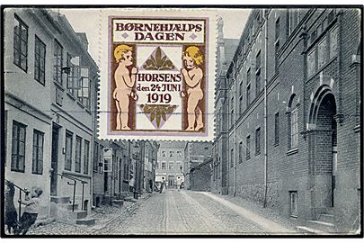 2 øre Bølgelinie og 5 øre Chr. X på brevkort med stor Børnehjælpsdagen Horsens den 24 Juni 1919 mærkat fra Horsens d. 24.6.1919 til Nykjøbing F. Mærkaten bundet til kortet af afsmitning fra maskinstempel.