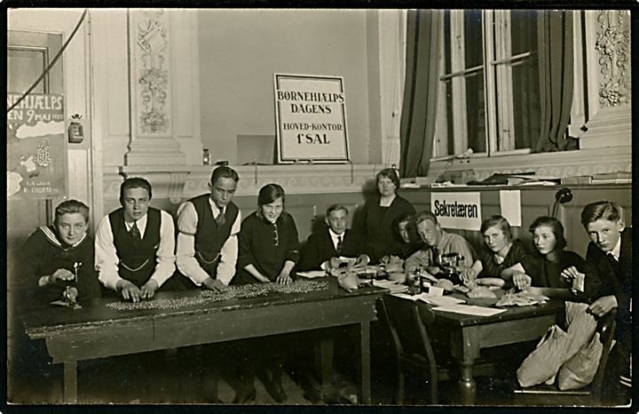 Børnehjælpsdagen 1923. Arbejde med optælling. I baggrunden resultat plakat tegnet af Storm P med angivelse af det indsamlede beløb i 1922. Fotokort u/no.