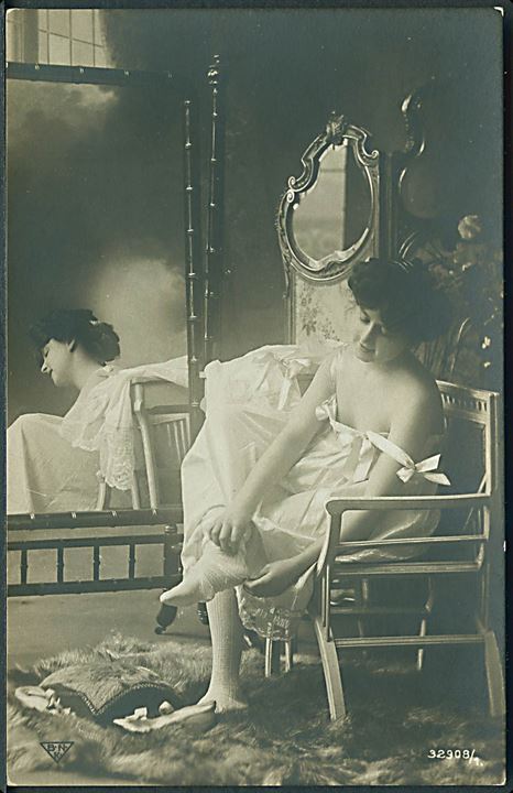 Kvinde sidder i stol. Ved at iføre sig tøj. Fotokort. B. N. K. no. 32908/1. 