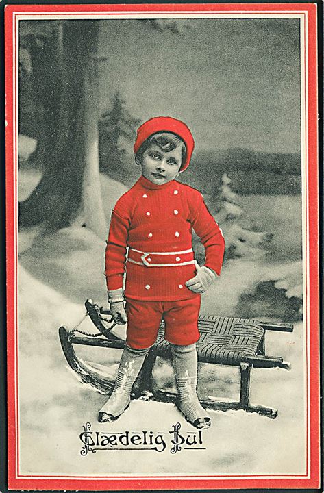 Glædelig Jul. Barn står ved kælk. Iført rødt tøj. Stenders u/no. 