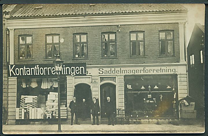 Herning, facade nr. 7 med “Kontantforretningen” og P. Jacobsen Saddelmagerforretning. Fotokort u/no. Kvalitet 7