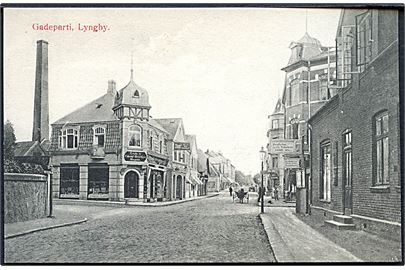 Lyngby, gadeparti med Lyngby ny Colonial Mel- og Gryn Magasin. G. M. no. 2556. Kvalitet 10