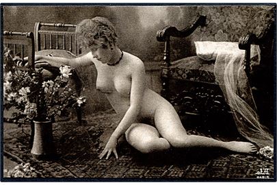 Erotisk postkort. Nøgen kvinde på tæppe. Vase med blomster og møbler omkring hende. Nytryk Stampa PR no. 234.   