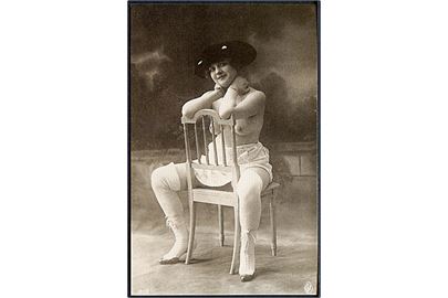 Erotisk postkort. Topløs kvinde iført sort hat. Sidder på stol. Nytryk Stampa PR no. 58.     