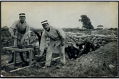 Soldater fra Sikringsstyrken i skyttegrav med slibesten. Fotokort u/no.