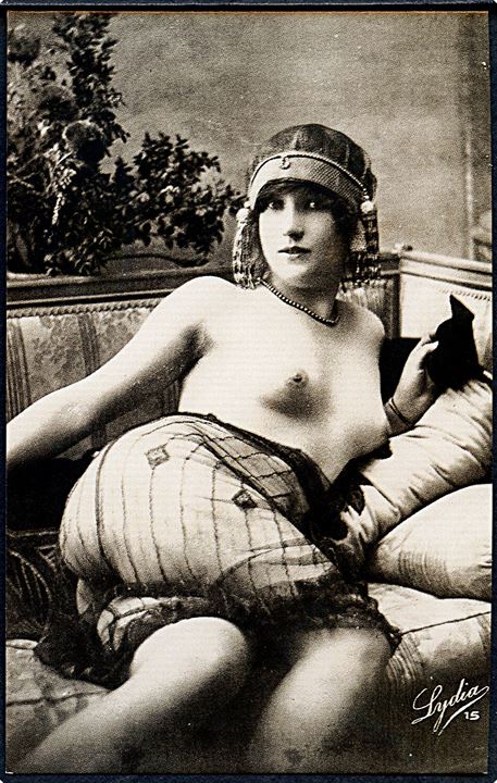 Erotisk postkort. Topløs kvinde ligger i sofa. Blondestof på underkroppen. Nytryk Stampa PR no. 85.  
