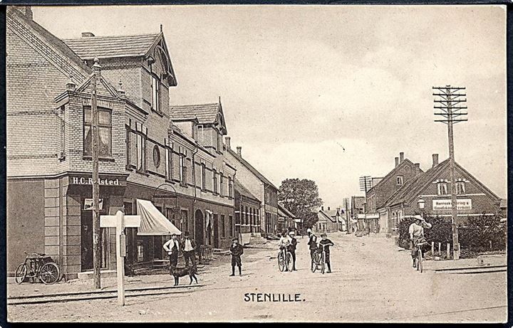 Stenlille, gadeparti ved jernbaneoverskæringen. Flere forretninger. L. Egemar no. 22744.