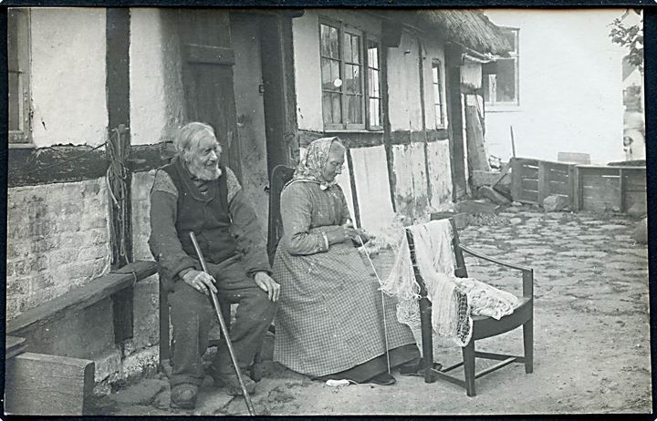 Bornholmsk type. Ældre ægtepar foran bindingsværk hus. Fotokort u/no.