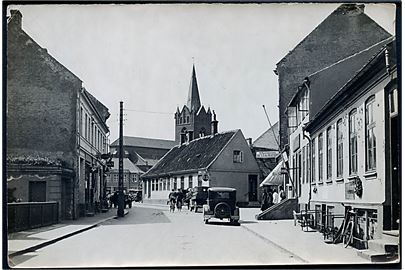 Slagelse, Smedegade med kirke i baggrunden. Fotografi 13x18 cm. Forlæg til fremstilling af postkort fra Robert Olsens Kunstforlag. 