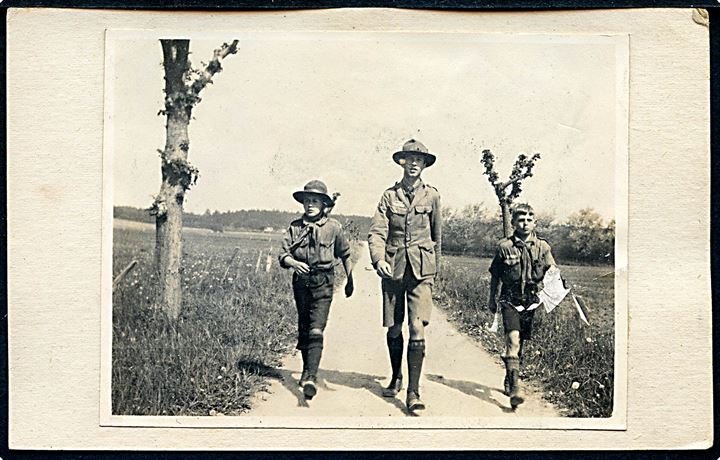 Spejderfører og to unge spejdere på march. Fotografi monteret på ubrugt postkort.