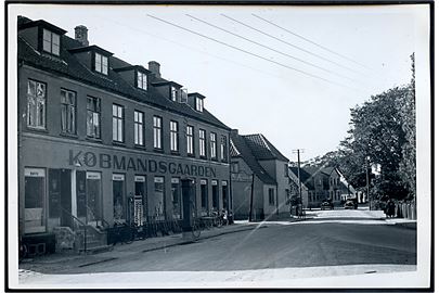 Hvalsø, gadeparti med Købmandsgaarden. Fotografi ca. 12x17 cm. Forlæg til fremstilling af postkort fra Rudolf Olsens Kunstforlag.