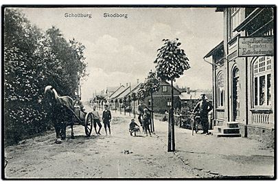 Skodborg, gadeparti med boghandel. W. Schützsack no. 28605. Frankeret med 7½ pfg. Germania annulleret med bureaustempel Sommerstedt - Schottburg Bahnpost Zug 53 d. 17.10.1916 til Heisagger.