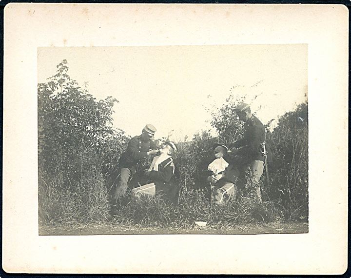 Soldater bliver barberet under kantonnementsøvelse i 1904. Foto monteret på karton. U/no.