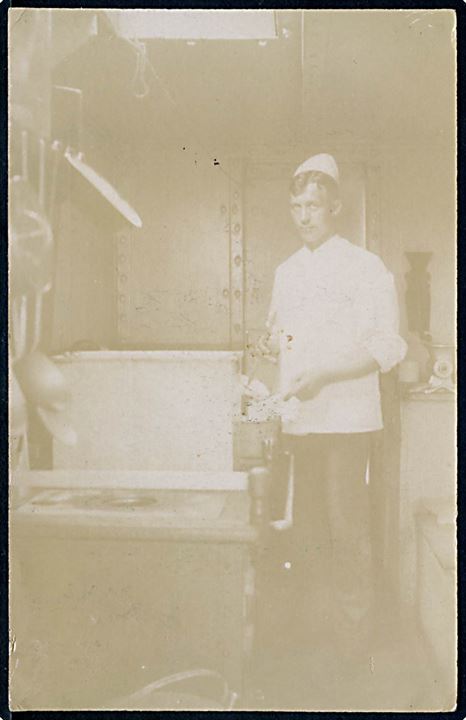 Skibskok i kabyssen. Fotokort sendt fra sømand ombord på S/S E.M.Dalgas i England 1910.