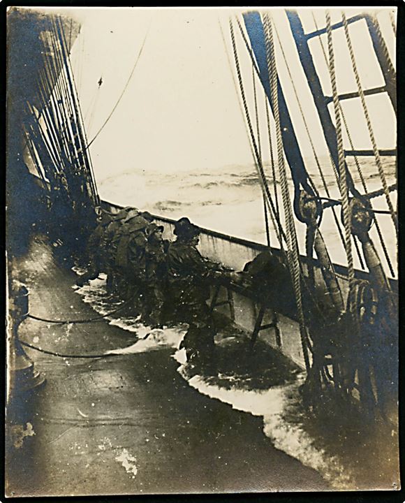 Sømænd på dæk ombord på stort sejlskib i hårdt vejr. Fotografi 10½x13 cm