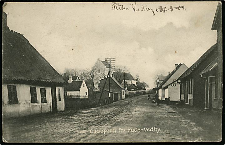 Ruds Vedby. Gadeparti med Bageri. Kirken i baggrunden. P.N. Sandfeld Petersen no. 5227.