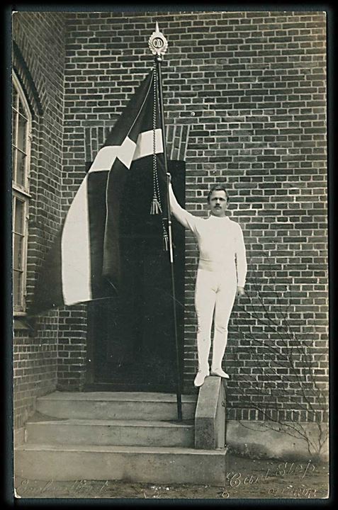 Mand med det danske flag foran Ollerup delingsførerskole. Carl Slej. Fotokort u/no. 