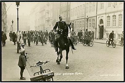 Købh., Chr. X rider gennem byen fulgt af cyklister. Stenders no. 4086.