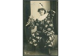 Kvinde iført klovnetøj holder en kat i nakkeskindet. D. L. G. no. 229/8. Fotokort. 