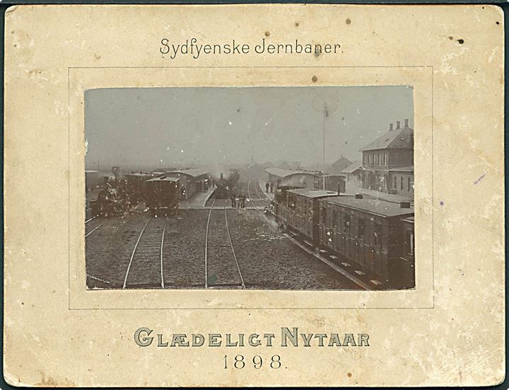 Ringe station. Sydfynske Jernbaners nytårshilsen 1898 med landkort. Kartonkort U/no. Div. skader. Kvalitet 5