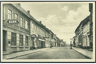 Adelgade i Bogense. Bank og Ford ses. Samt benzinstander Esso. Rudolf Olsens Kunstforlag no. 3894.