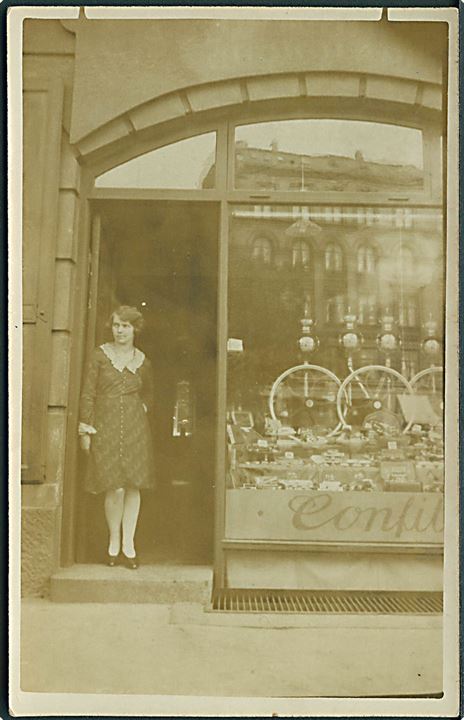 Kvinde ved indgang til kaffe og chokoladeforretning. Fotokort u/no.