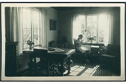Kvinde sidder i stuen og strikker. Sted ukendt. Anvendt i Rønne. Fotokort no. 10. 