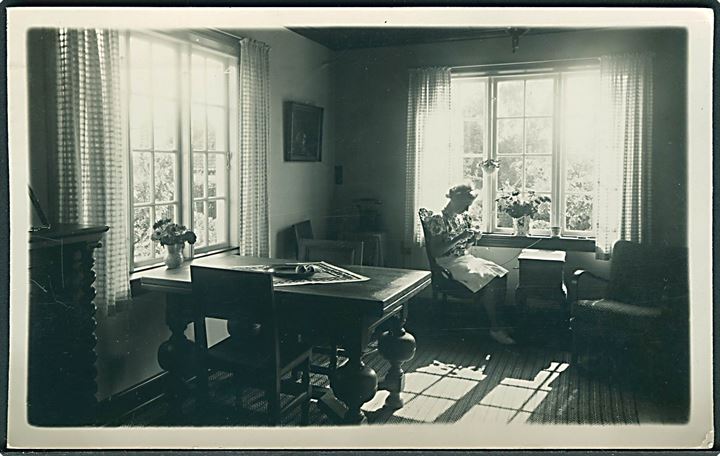 Kvinde sidder i stuen og strikker. Sted ukendt. Anvendt i Rønne. Fotokort no. 10. 